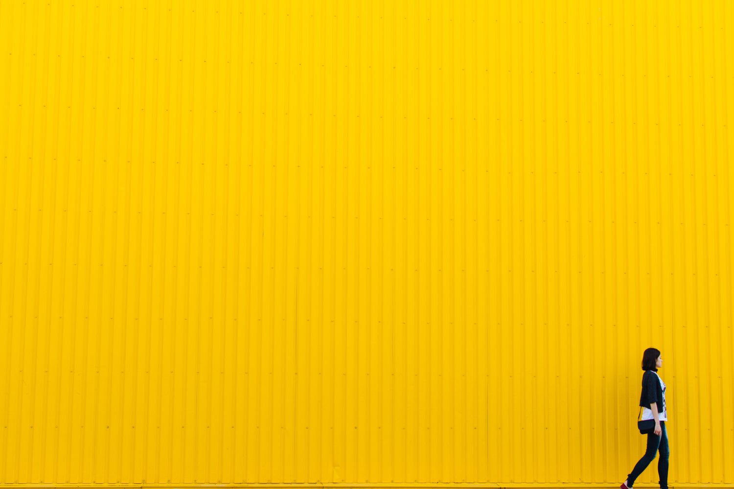 Woman standing next to yellow wall Woman standing next to yellow wall